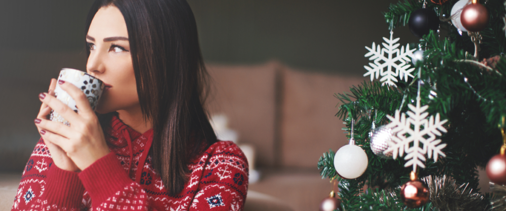 woman relaxing with a hot drink by the Christmas Tree to show she is relaxed