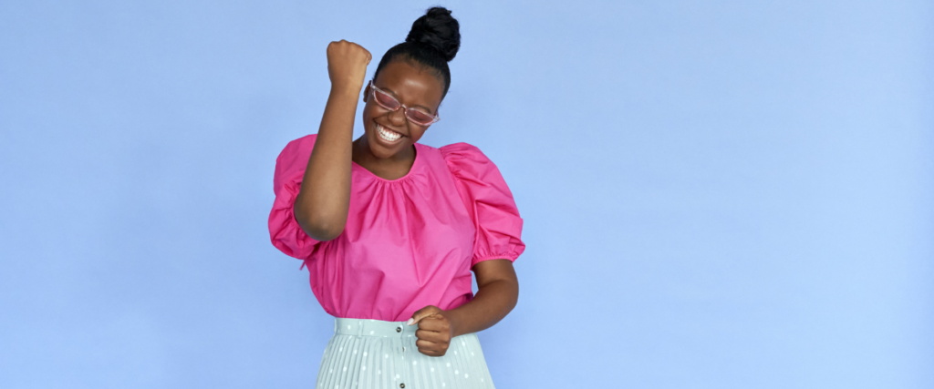 Woman in a pink top with her arm in the air to show success and happiness