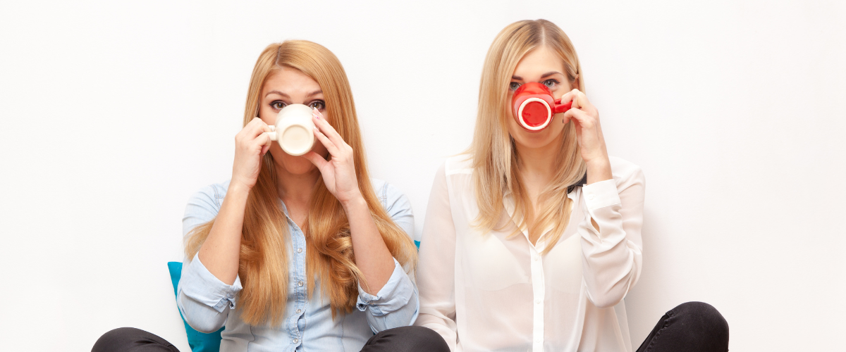 two women sitting on the floor drinking coffee to show they are not people pleasing